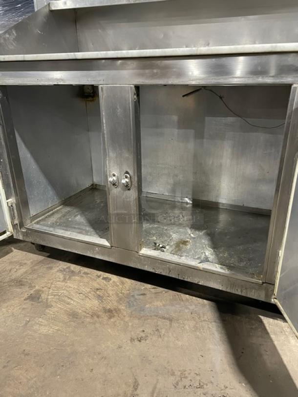 Bari 3-door stainless steel pizza prep/dough retarder table with a marble-style worktop on casters; interior shows wear.