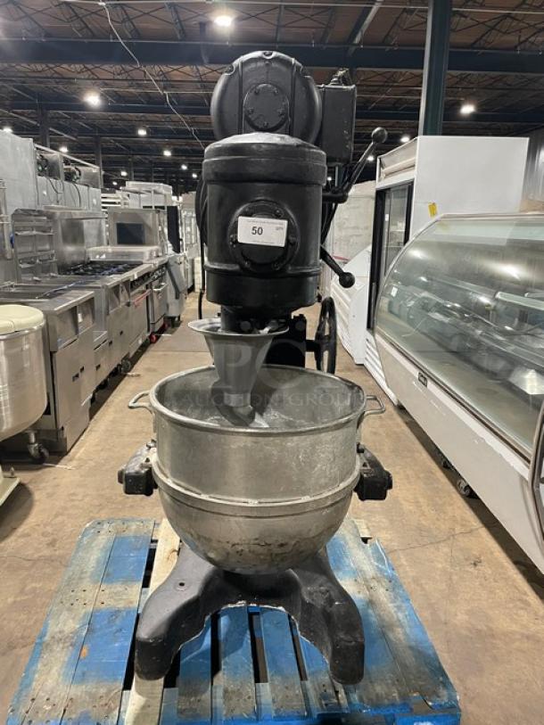 Commercial black electric-powered heavy-duty planetary mixer with stainless steel bowl and spiral dough hook on legs.