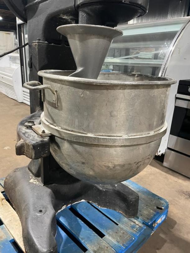 Commercial black electric planetary mixer with stainless steel bowl and spiral dough hook. Heavy-duty, free-standing on legs.