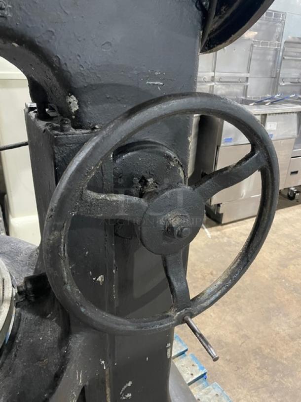 Commercial black electric planetary mixer with stainless steel bowl and spiral dough hook. Heavy-duty, free-standing on legs.
