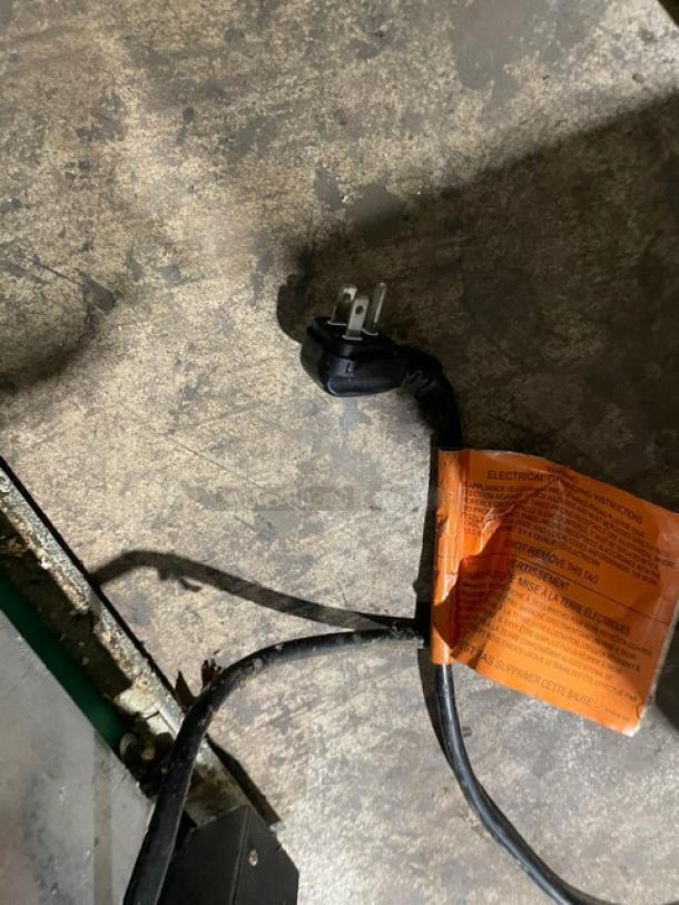 Close-up of a power cord with an orange warning tag, possibly from a commercial refrigerator. Condition is used.