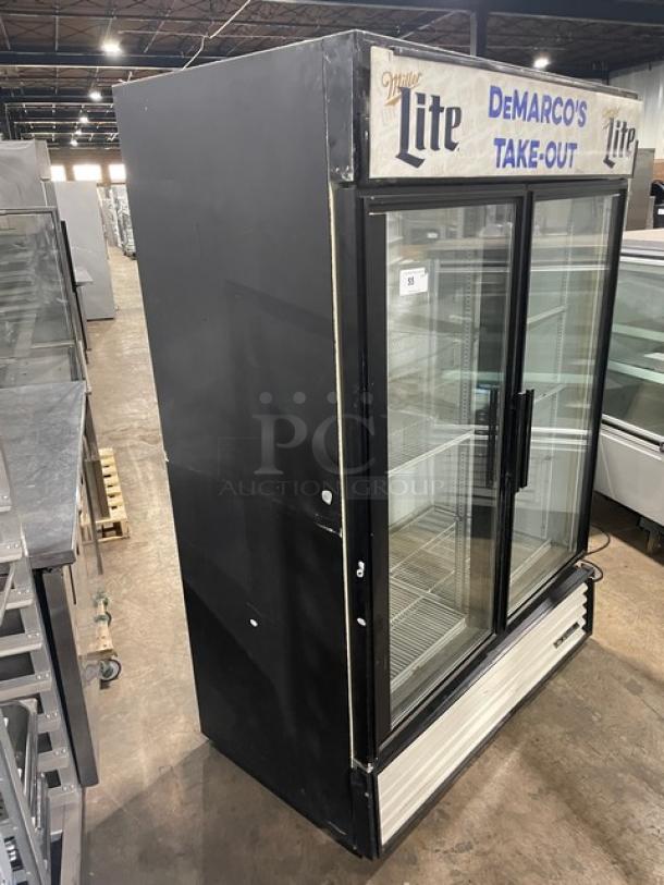 True GDM-49 commercial fridge with double glass doors, poly-coated wire racks, "DeMarco's Take-Out" sign. Model GDM-49, 115V.