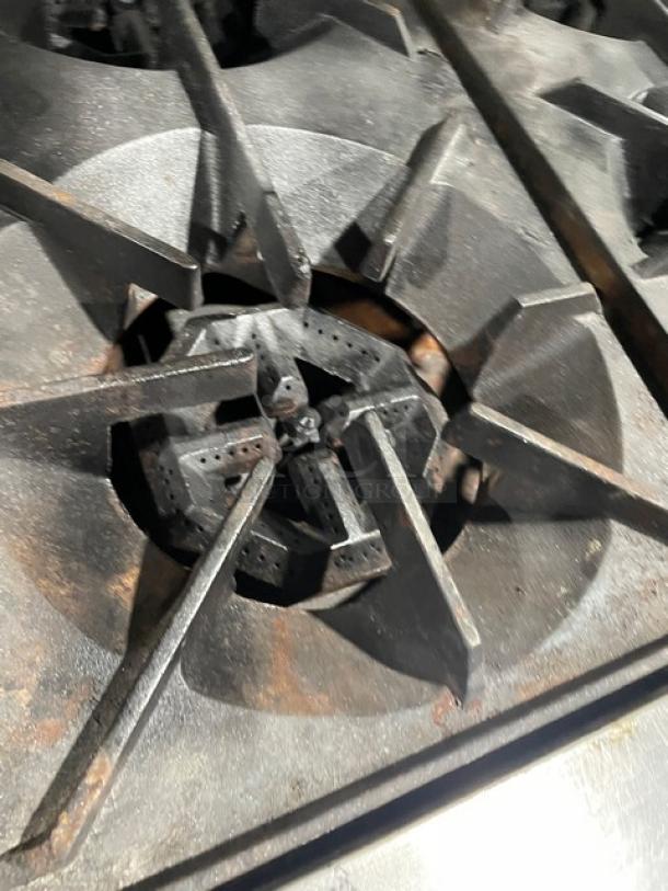 U.S. Range commercial stainless steel natural gas 6-burner top view. Features robust cast iron grates. Used condition.