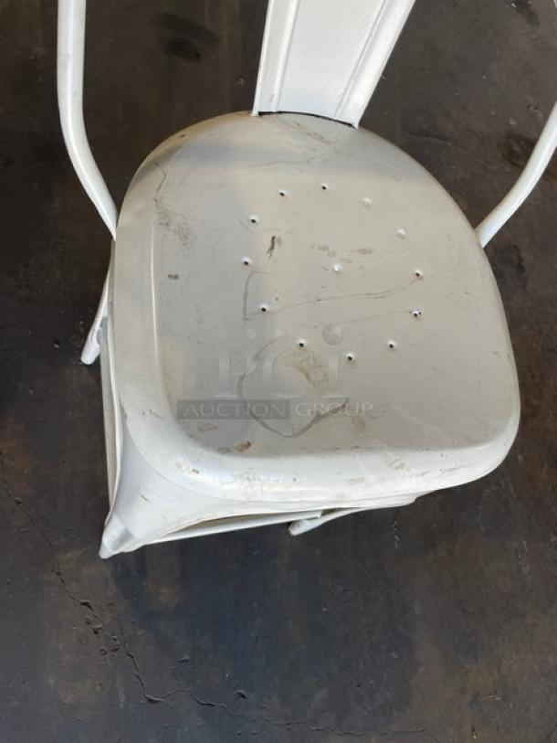Distressed white metal bistro style bar-height stool, suitable for indoor-outdoor use; features visible wear for vintage appeal.