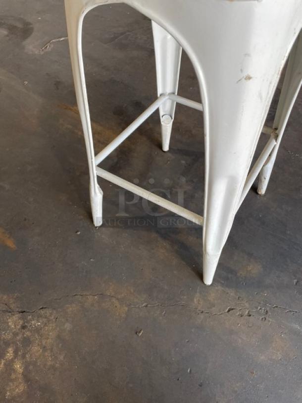 Distressed white bistro-style bar-height stool, suitable for indoor-outdoor use. Sturdy metal construction, rustic finish.