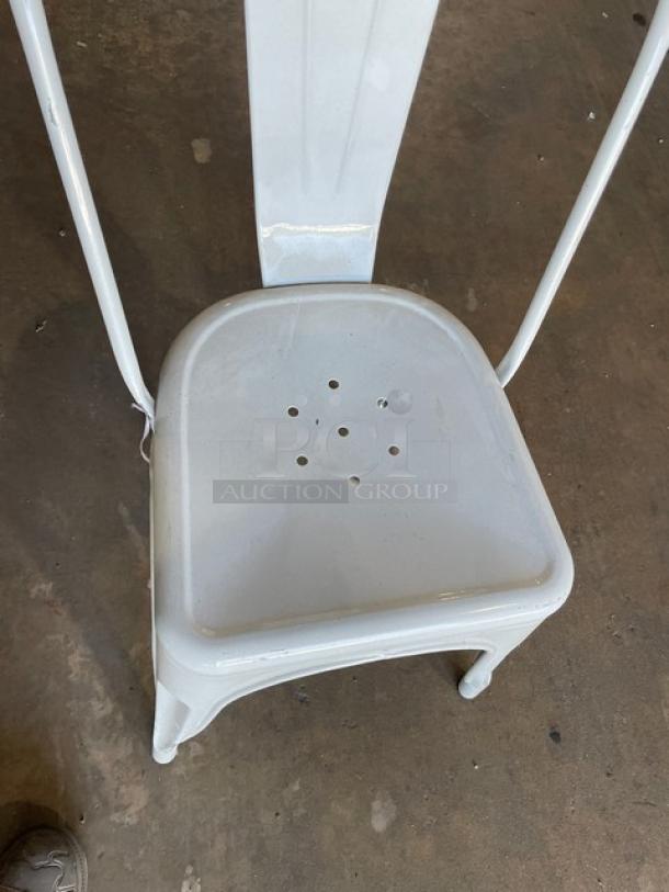 Distressed white bistro-style dining chair, stackable, for indoor-outdoor use. Slight wear, perforated seat, commercial quality.