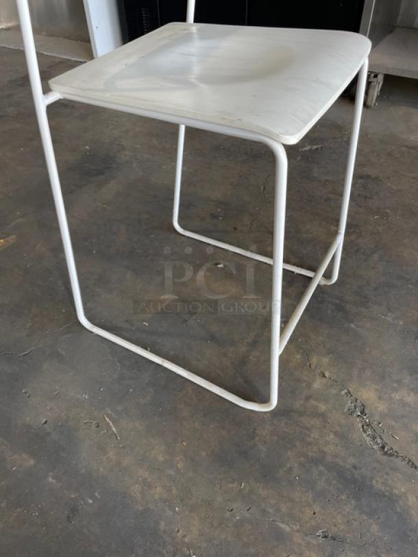 White metal-framed dining chair with wooden-style seat. Stackable design, suitable for indoor and outdoor use. Good condition.