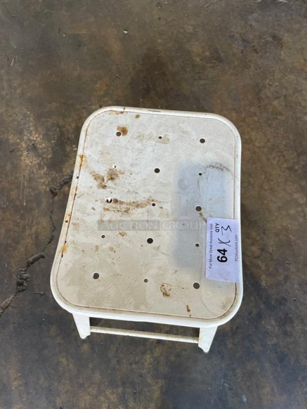 Distressed white metal stackable bar-height stool, suitable for indoor-outdoor use. Visible wear, numbered tag "64" attached.