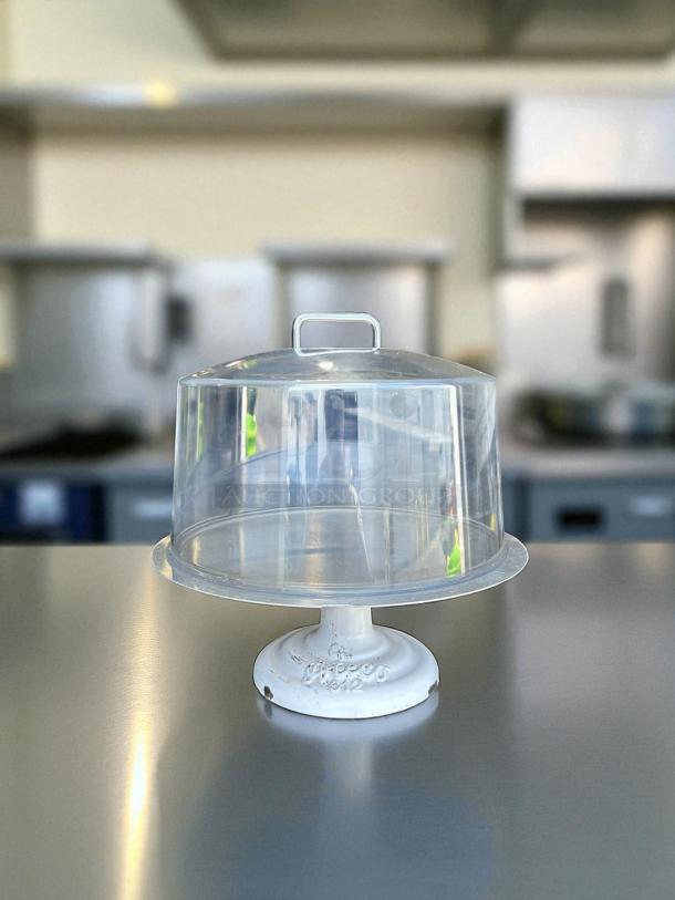 Heavy-duty cake display stand in great condition with clear cover. White base with embossed markings, ideal for showcasing cakes.