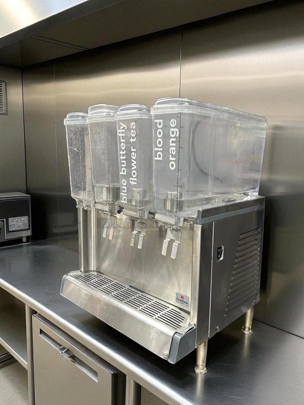 Crathco CS-4E-2/3D-16 cold beverage dispenser with four bowls, 120V, like-new condition, labeled for teas and juices.