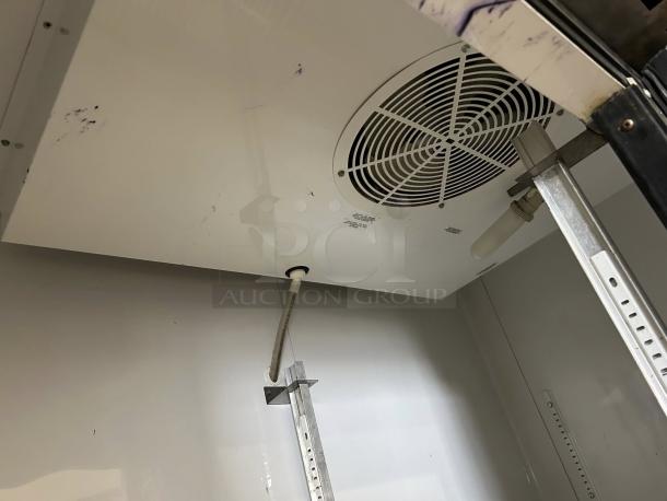 Interior view of a True T-49 refrigerator showing a fan and shelving supports, indicating its great condition and functionality.