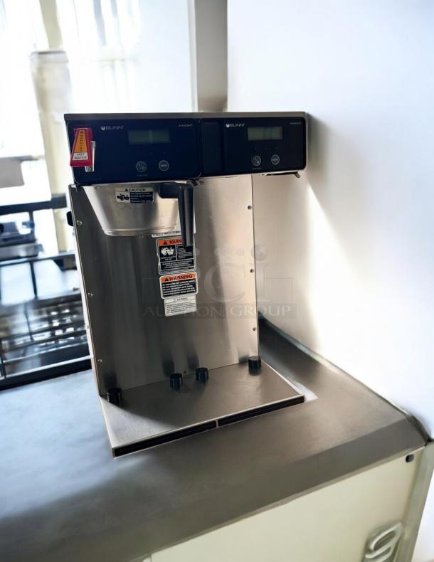 Bunn Axiom Twin APS coffee brewer in excellent condition, 120/208–240V, tested and working with warning labels visible.