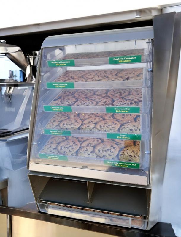 Nemco 6490-SUBA Cookie Display Case in great condition, 24"H x 17"W x 12"D, showcasing various cookie trays with labels.