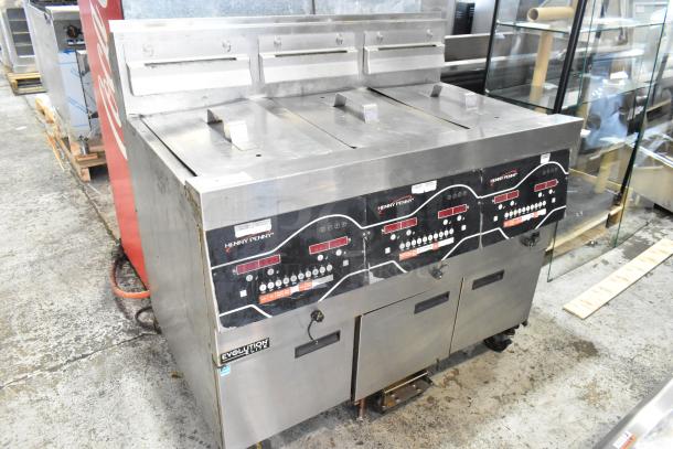 Henny Penny EEG-243 FFFX ST commercial 3-bay deep fryer, stainless steel, natural gas, 225,000 BTU, on casters with lids.