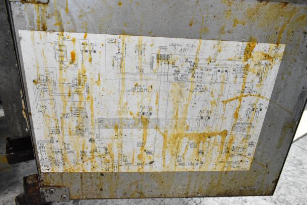 Stained diagram on Henny Penny EEG-243 FFFX ST fryer's stainless steel body. Visible wear and grime. Technical schematics.