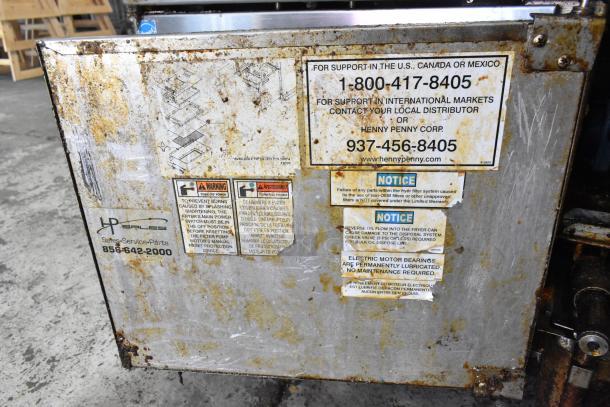 Henny Penny EEG-243 FFFX ST stainless steel commercial fryer with filtration system; labels show contact info and warnings.