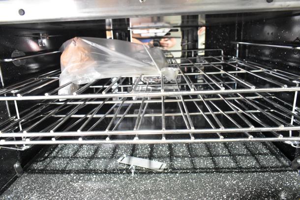 Interior view of the 2021 Venancio R602CO-60B convection oven. Stainless steel racks, plastic-wrapped accessories visible. New condition.