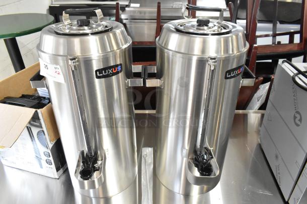 2 new Fetco TPD-30 Luxus 3-gallon stainless steel coffee dispensers, with tags and minor scratches, increasing auction bid.
