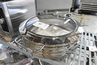 "Brand new stainless steel round chafer with glass lid, visible minor scratches. Auction tag indicates item number 63."