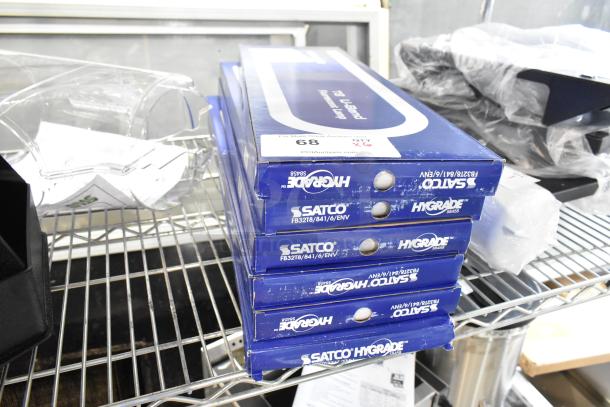 Six new Satco S8458 HyGrade 32W Cool White U-Bend T8 bulbs in scratched boxes on a metal shelf.