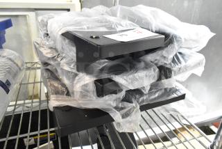 Six brand new Choice Smoke Black Condiment Caddies, model 176NDPLCDYBK, wrapped in plastic on a shelf, for napkin dispensers.