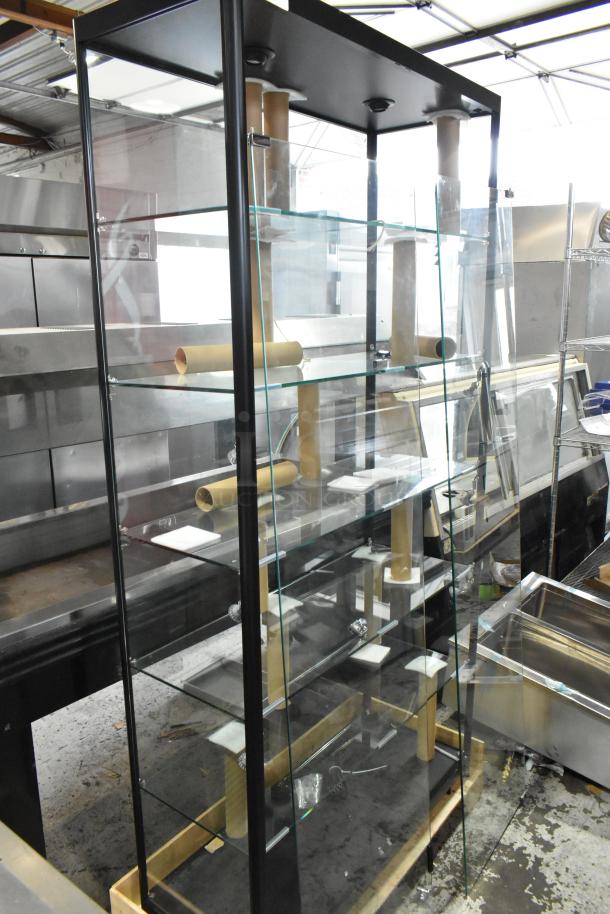Clear glass and black metal dry merchandising display case with multiple shelves, in good condition. Suitable for retail showcasing.