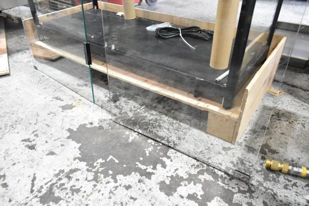 Glass dry merchandising display case with black shelving, visible cable, and wooden base. Appears in good condition.