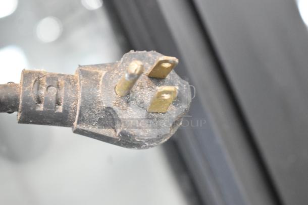 Close-up of a dusty power plug for an Imbera VRD37 commercial cooler, emphasizing electrical connection details.