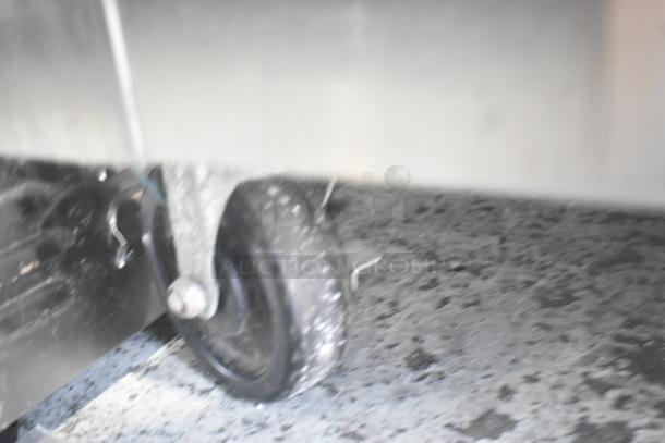 Blurred close-up of the caster wheel on a Traulsen RHT232WUT-FHS stainless steel commercial cooler.