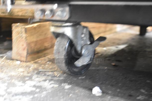 Close-up of a True TM-52F freezer caster. Visible metal frame and wheel. Signs of wear on the surface.