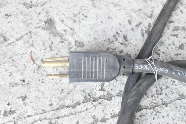 Close-up of a black power cord with a three-prong plug, showing text "DUAL RATED MADE" on the cable.