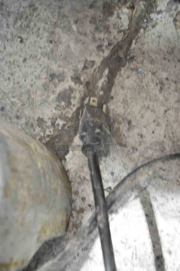 Dirty power cord ending against a textured, worn concrete surface.