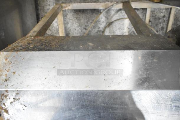 Metal commercial floor marinating station with visible rust and wear, featuring a sturdy metal frame and flat surface.