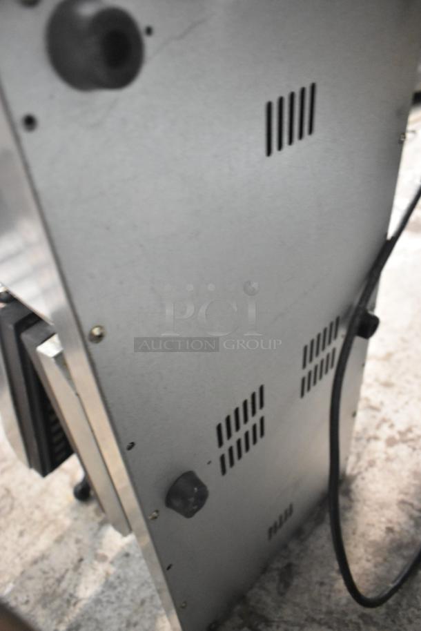 Stainless steel commercial countertop waffle maker, showing side panel with vent and knob, used condition.