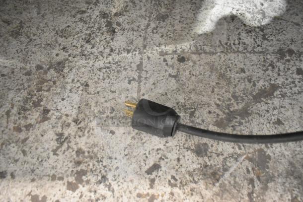 Electrical plug on a speckled countertop. Part of the stainless steel commercial countertop waffle maker setup.