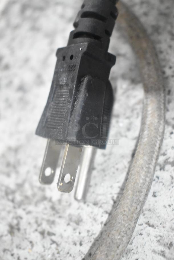 Close-up of a plug attached to a 2022 metal commercial countertop heated display case merchandiser, 110 volts, 1 phase.