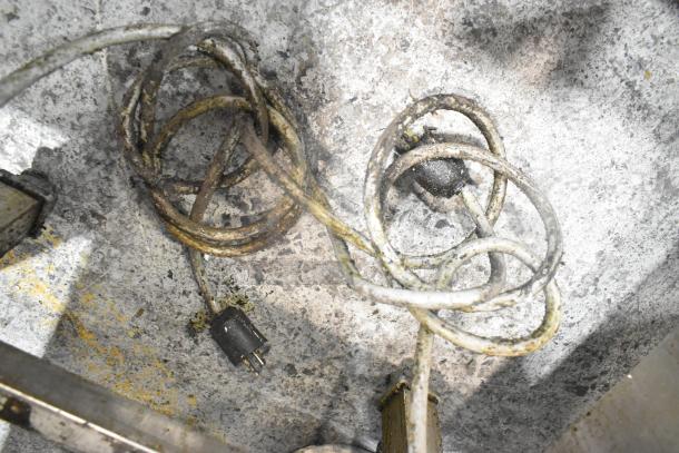 Coiled power cords on a worn, textured surface, possibly part of a commercial kitchen appliance setup.