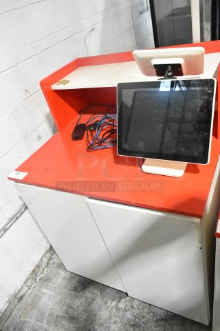 White and red counter with POS monitor, good condition, includes cables and storage cabinets, lot number 125 visible.
