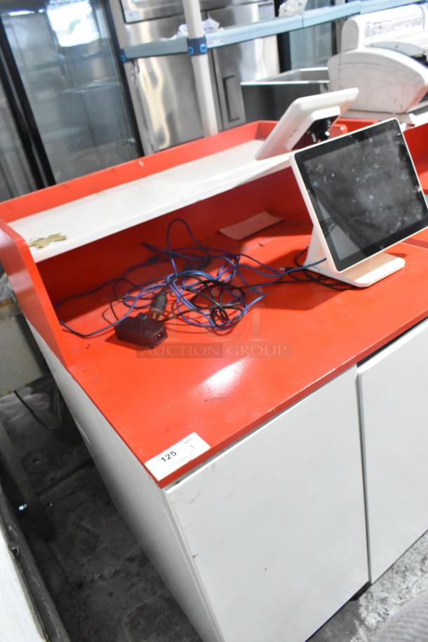 White and red counter with POS monitor, slightly worn. Includes cables. Item tag reads "125". Suitable for retail settings.