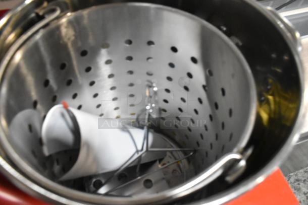 Brand new stainless steel deep fat fryer stock pot, shows light scratches, features perforated basket and hooks, perfect for large batch frying.