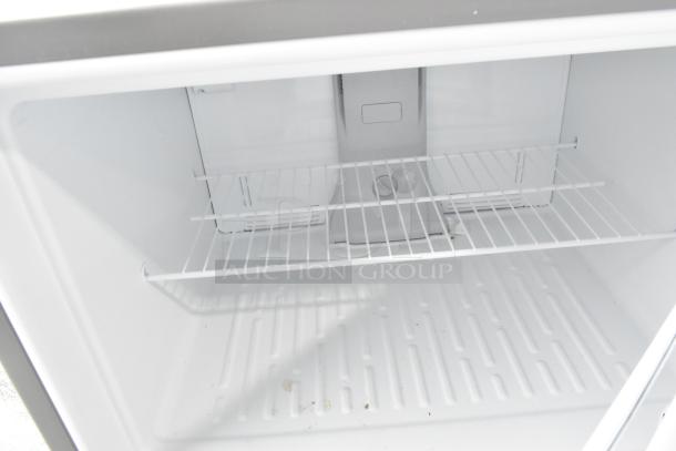 Interior of brand new Whirlpool WRT311FZDM05 stainless steel commercial cooler with wire shelf. Minor scratches visible.