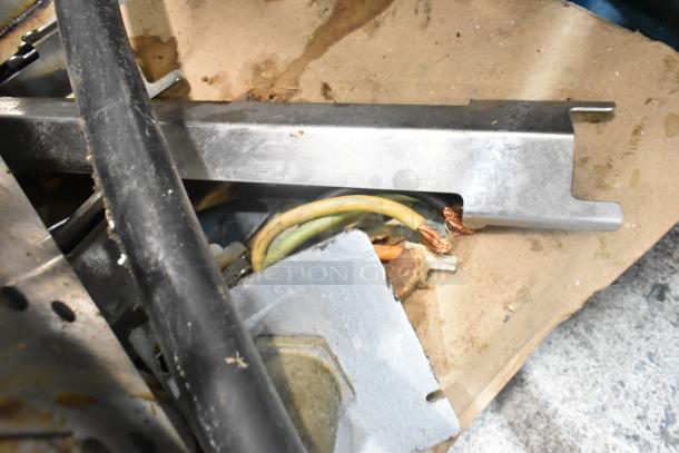 Alt text: Close-up of damaged wiring and components from an Alto Shaam AR-7T rotisserie oven, showing frayed wires and metal parts.