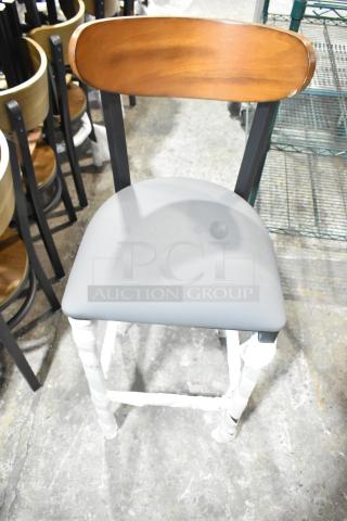 Black metal bar-height chair, brand new, with a wooden backrest and gray cushion seat. Some minor scratches.