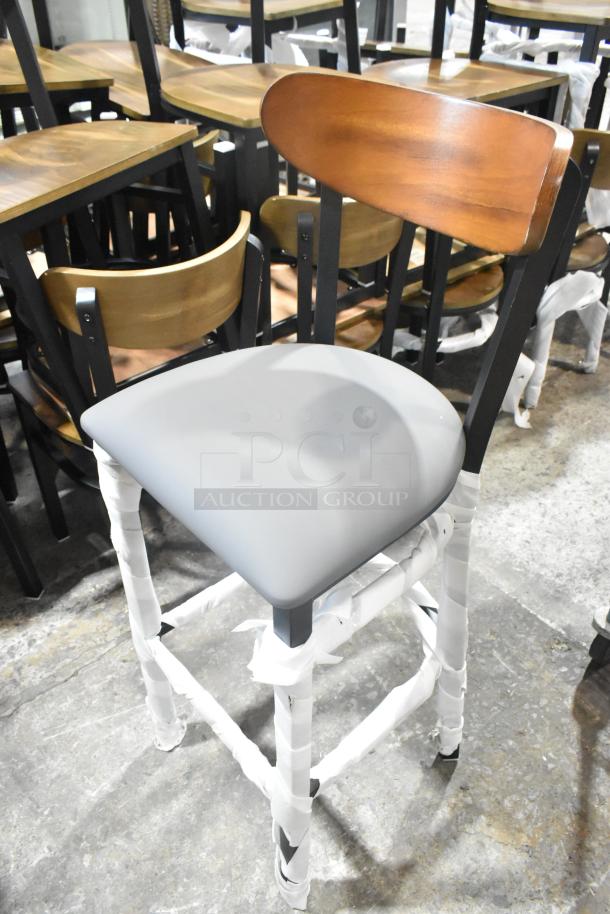 Black metal bar height chair, wooden backrest, gray cushion seat. New, scratch and dent condition.