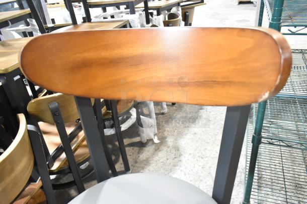 8 brand new black metal bar height chairs with wooden backrest and gray cushion seat, minor scratches visible.