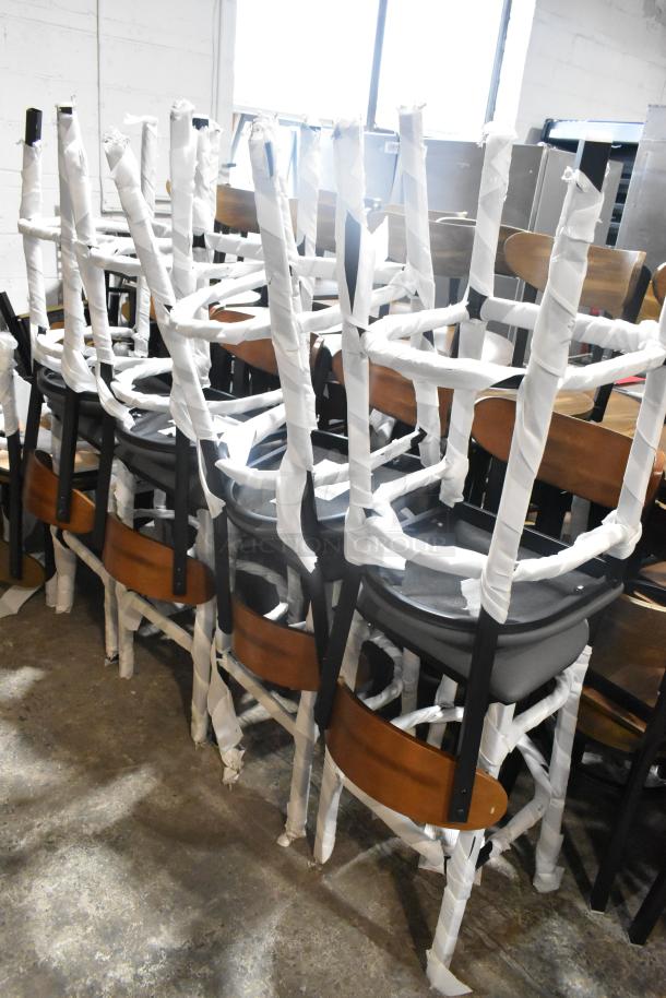 8 new black metal bar-height chairs with wooden backrests and gray cushion seats. Wrapped in protective material.