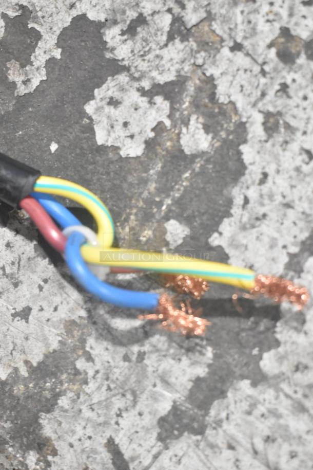 Three exposed wires with copper ends, covered in red, blue, and yellow insulation, on a textured gray surface.