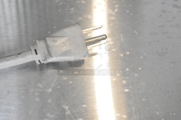Power plug of Solwave 180MW1000SS microwave on stainless steel surface. New condition with noticeable scratching.
