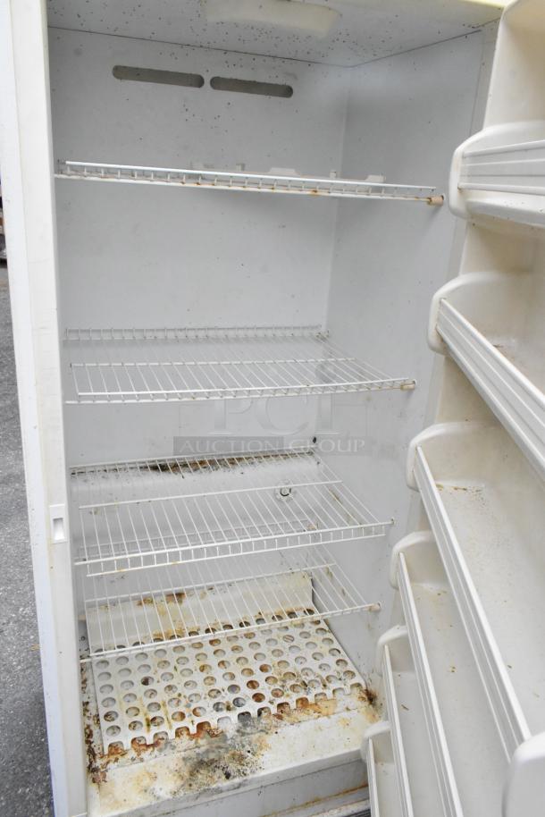 Frigidaire FFUH21F2NWA reach-in metal freezer, visible interior shelves, signs of rust and wear, 115 volts, 1 phase.