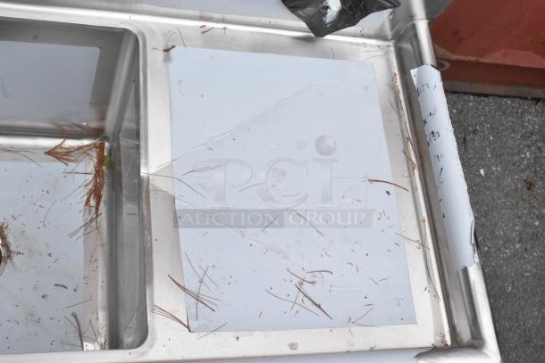 BRAND NEW Regency 600S21818218 stainless steel 2-bay sink with dual drain boards. Scratch and dent. Minor wear visible.